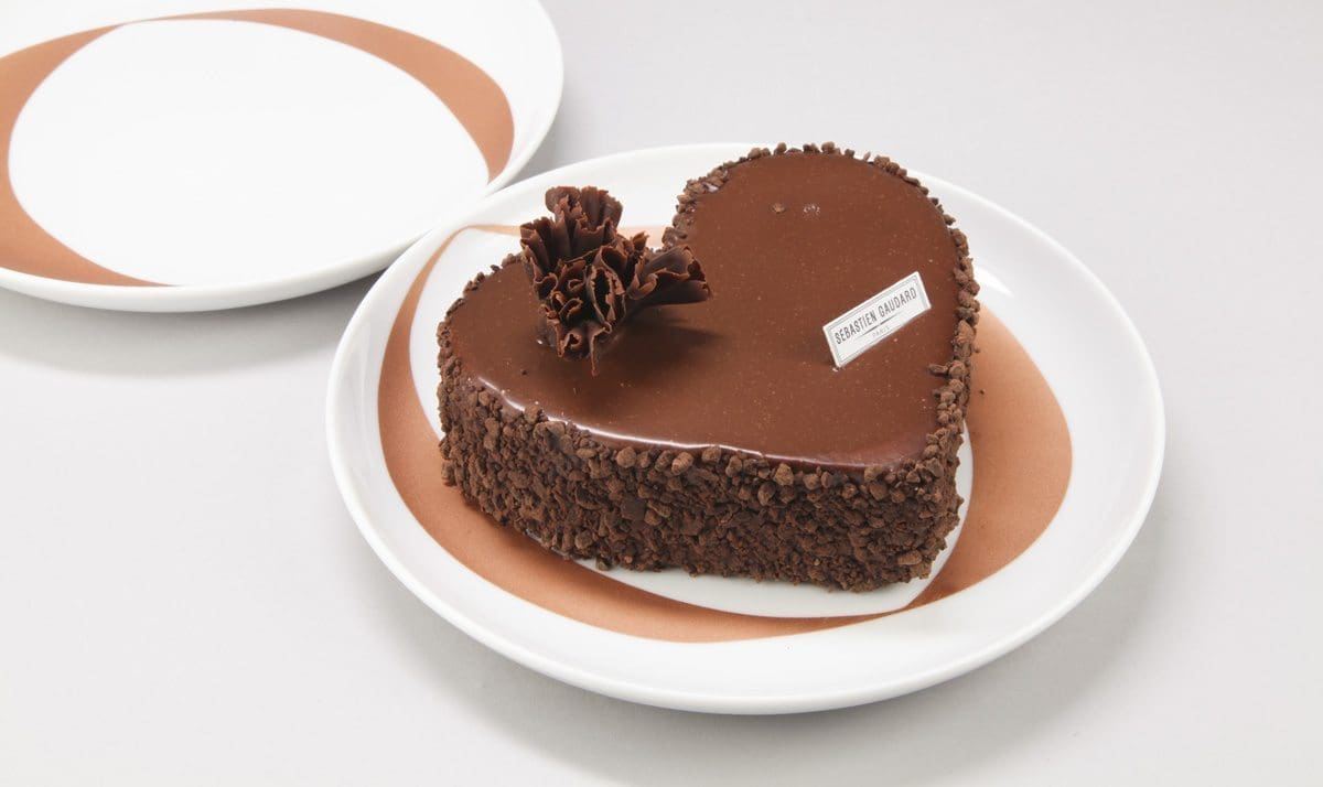 Assiettes infini : Deux assiettes blanches ornées d'anneaux cuivrés. Assiettes à desserts pour amoureux. Sur une des assiette, est posé un gâteau en forme de coeur, un Mussipontain du pâtissier Sebastien Gaudard. Assiettes crées pour la DesignerBox 21 par Ich&Kar