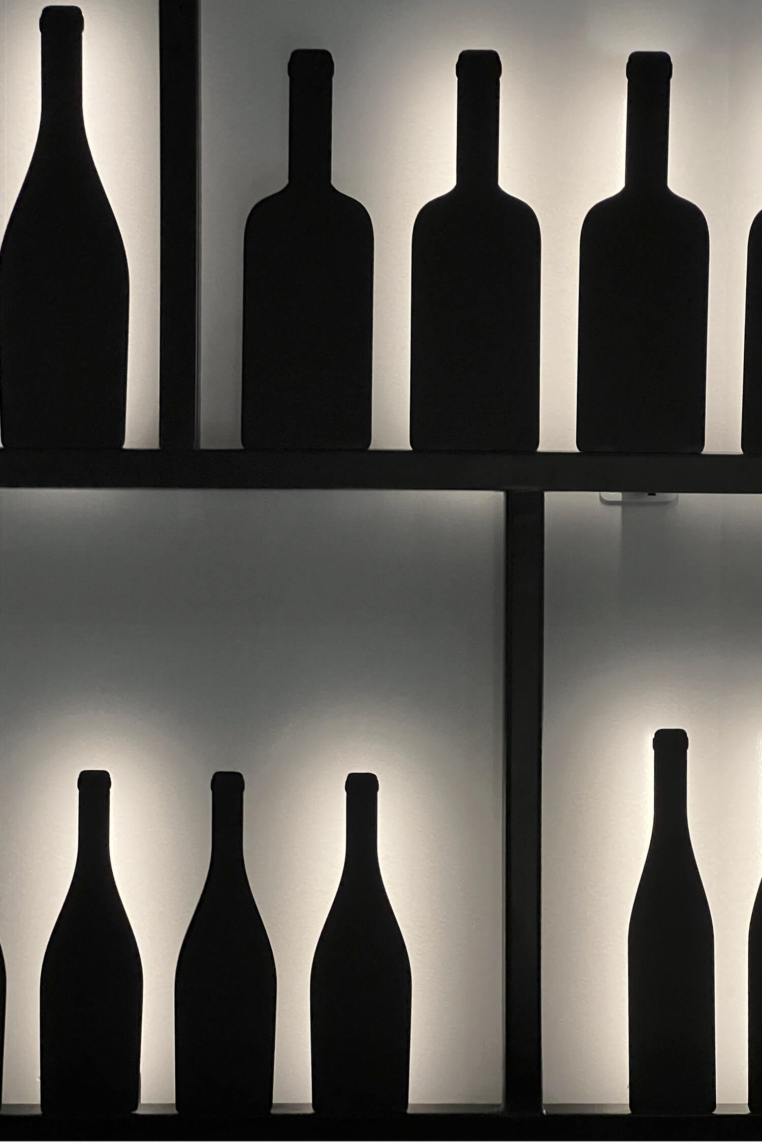 Zoom sur le mur dessiné par IchetKar, bouteilles et étagères en metal noir, rétro éclairées façon ombre chinoise